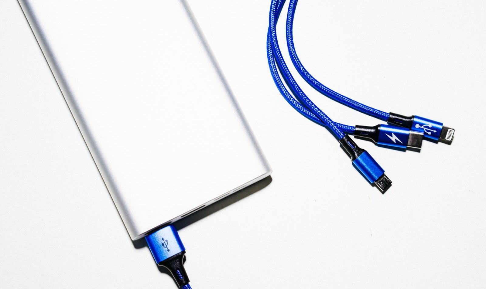 Білий повербанк з кабелями USB на білому фоні